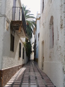 a narrow Spanish street with buildings on either side